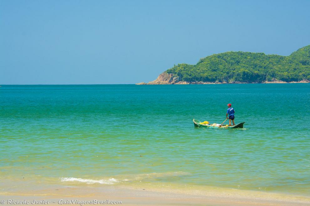 Imagem de uma pescador nas águas azulada da Praia da Almada em Ubatuba.